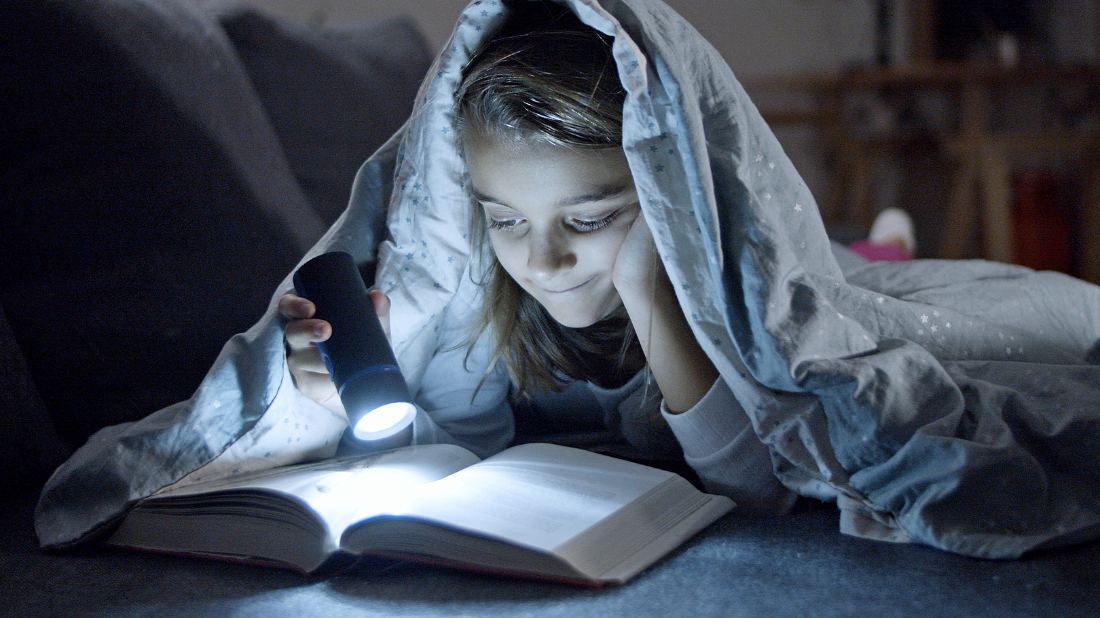 dziewczynka oświetla książkę latarką dziewczynka oświetla książkę latarką