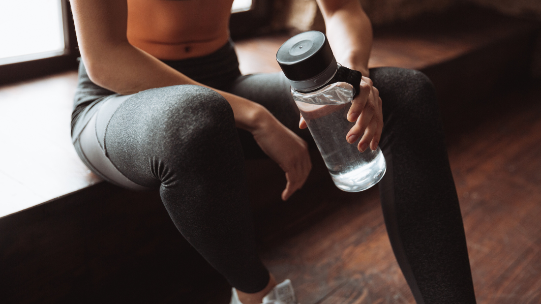 Kobieta z butelką wody podczas przerwy od ćwiczeń Kobieta z butelką wody podczas przerwy od ćwiczeń